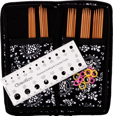 ChiaoGoo double pointed bamboo knitting needle set with white knitting needle gauge, pink and yellow stitch markers, and a black and white fabric needle case.
